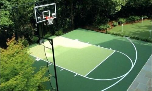 terrain de basket vert avec ligne blanche entouré d'arbres